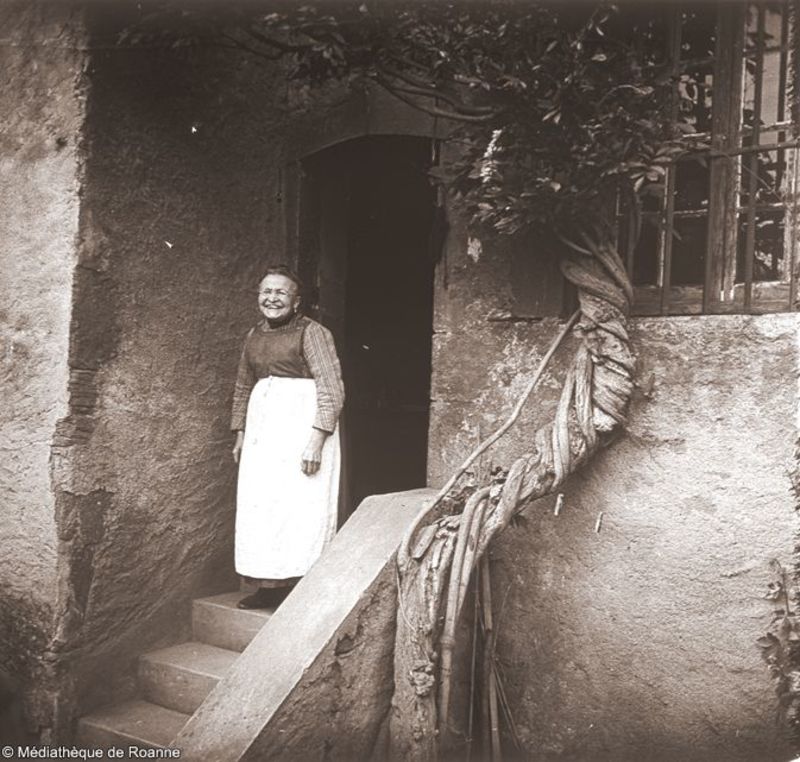 Charlieu - Femme souriante sur un porche de maison