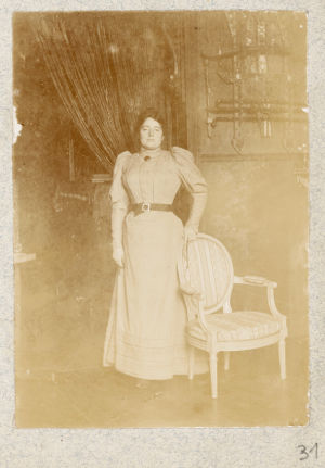 Anonyme. Lili Grenier debout à côté d'une chaise​​​​​​​.